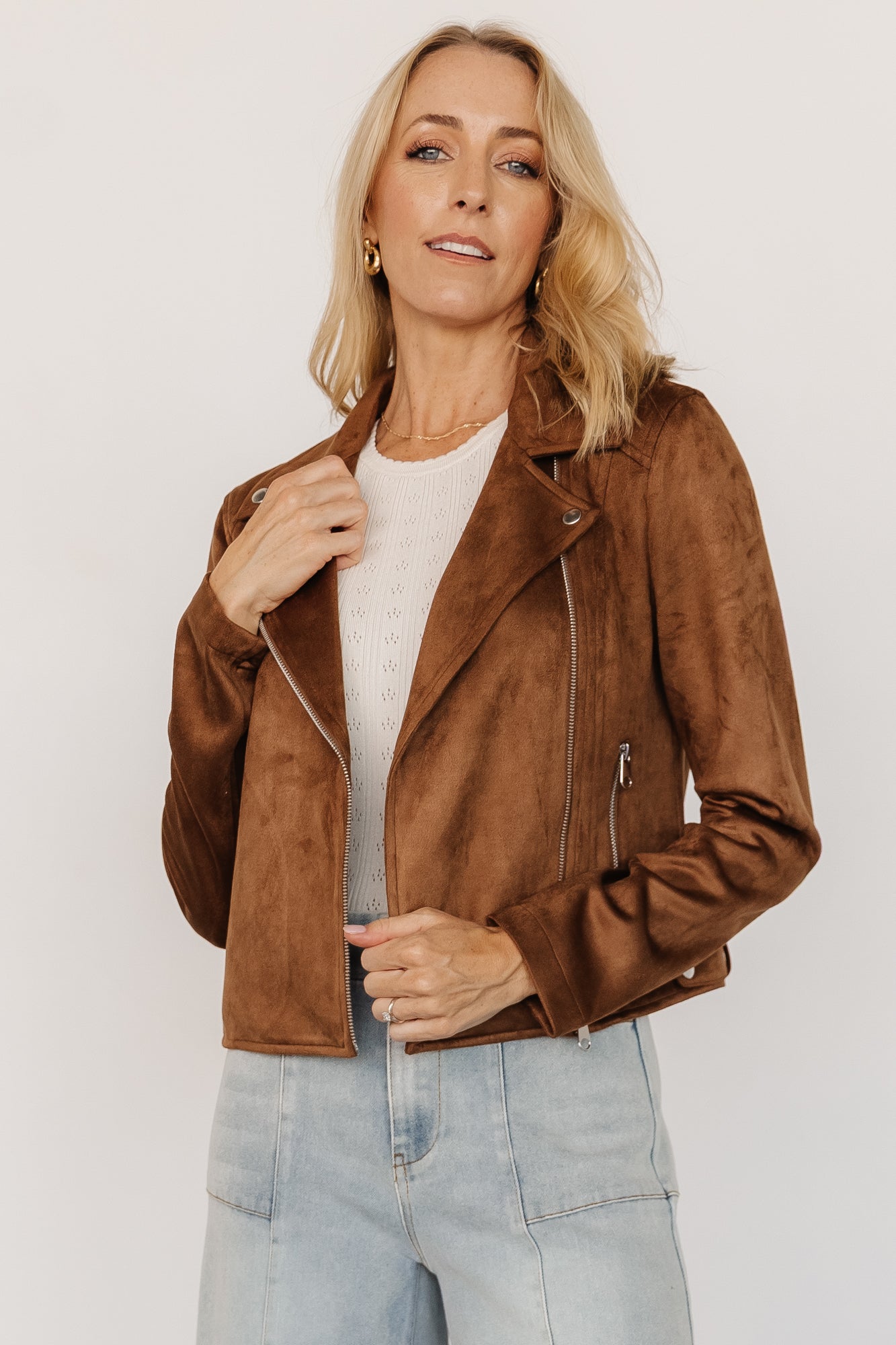 Front view of the Marisa faux suede moto jacket in caramel on a model, showing zip pockets, cropped hem, collar, and asymmetric zip details.