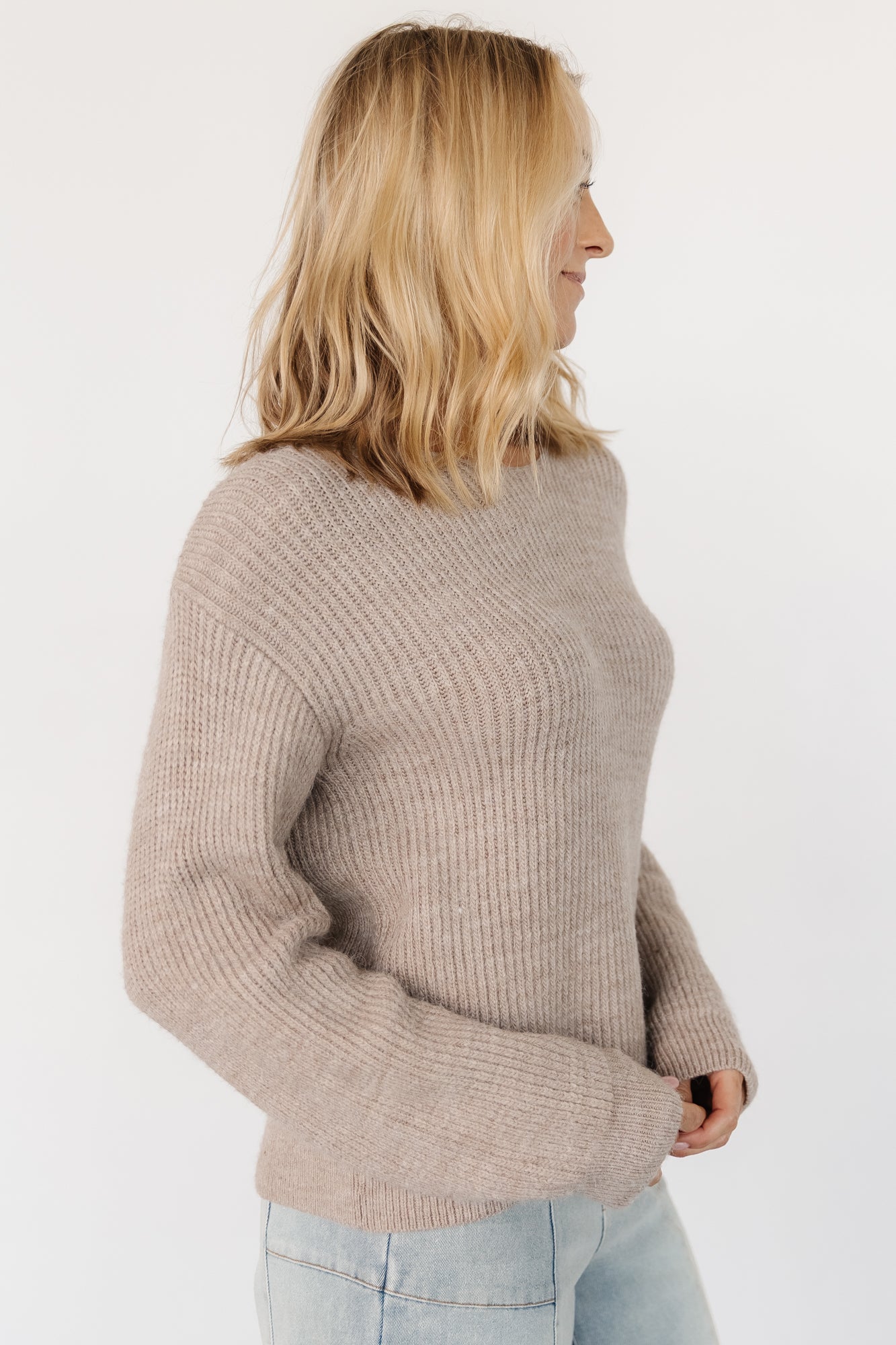 Side-angle shot of Viola Tie Back Sweater in Natural on a model, showing drape of the knit, sleeve length, and overall silhouette.