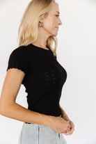 Detail shot of the Penny Pointelle knit fabric in black, focusing on the pointelle eyelet pattern, ribbing, and scalloped neckline finish.