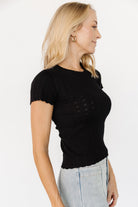 Close-up of Penny Pointelle top in black highlighting ribbed detailing, delicate eyelet pointelle pattern, and scalloped trim at the sleeve cuff.