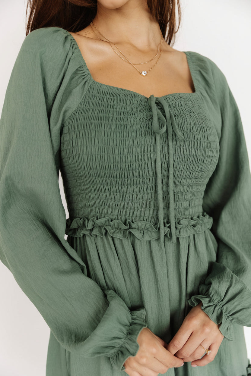 Back and side view of the Britta Maxi Dress in dark sage illustrating sleeve length, elastic cuffs, and tiered skirt movement.