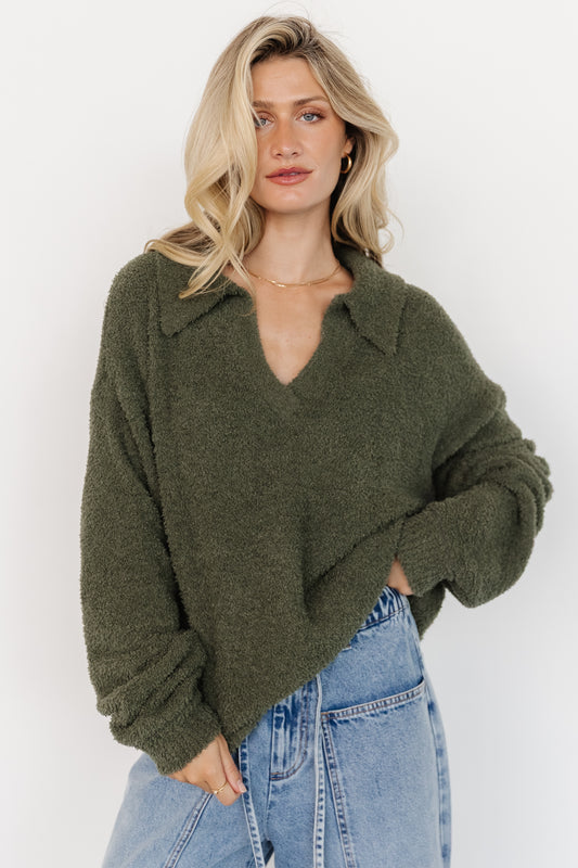 Side-angle of Lockwood sweater on model emphasizing relaxed silhouette, collared V-neck and sleeve length in muted green.