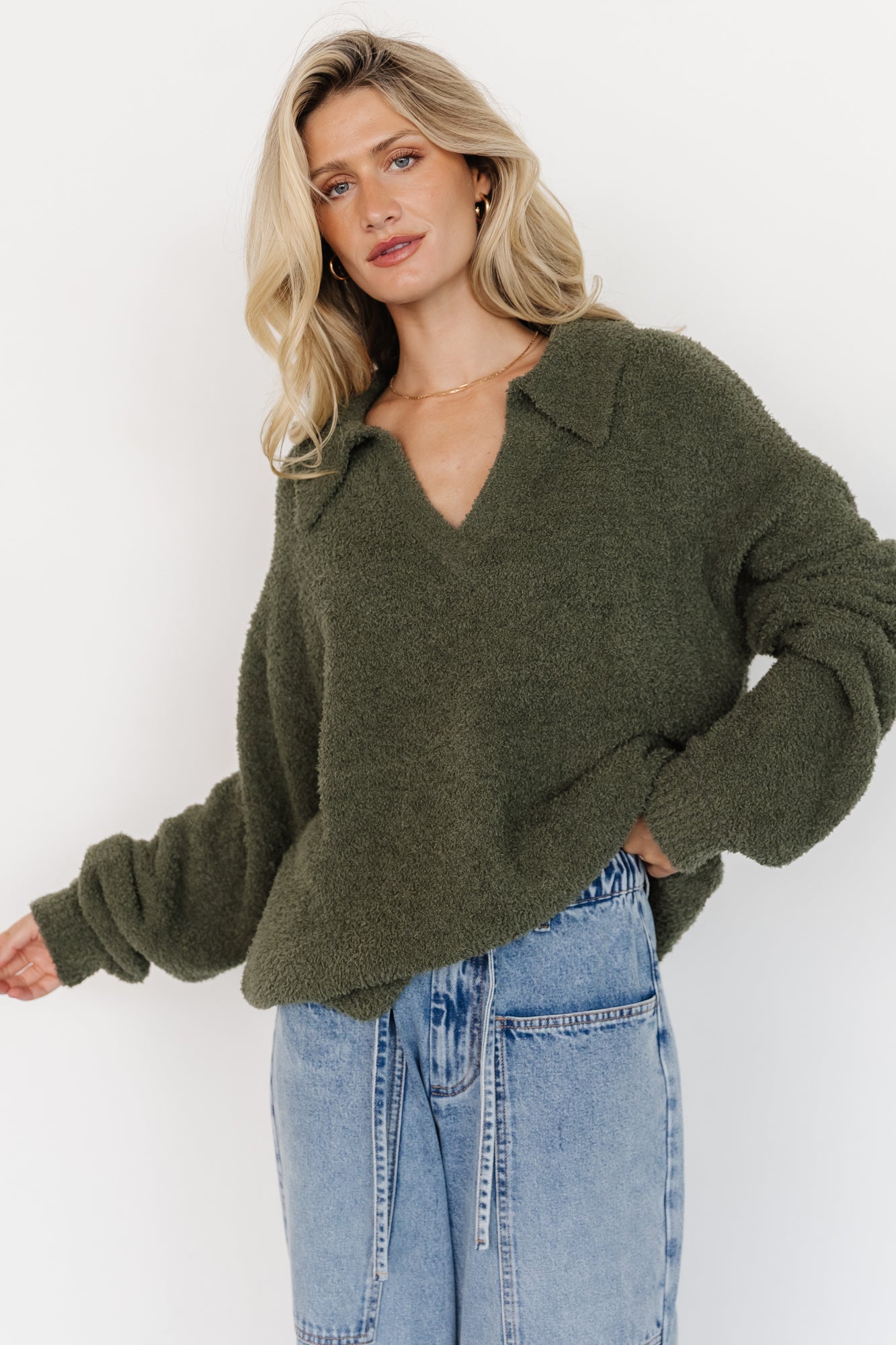 Model wearing Lockwood sweater in muted green, front view showing collared V-neck, long sleeves, ribbed hem and fuzzy knit texture.
