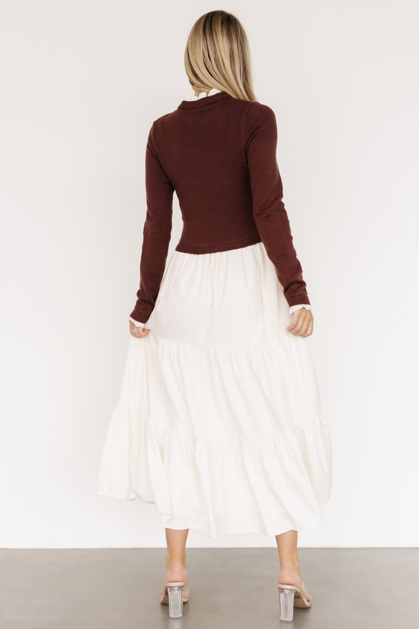 Side view of model in Sophie Sweater Dress mahogany and ivory, displaying the small ruffle at the cuff and the skirt's tiered silhouette in motion.