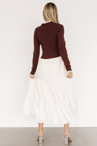 Side view of model in Sophie Sweater Dress mahogany and ivory, displaying the small ruffle at the cuff and the skirt's tiered silhouette in motion.