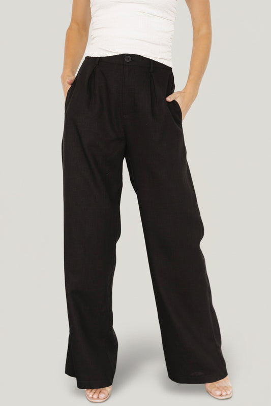 Front model shot of Malin wide leg pants in black, showing the smocked back waist, tailored front crease, and flowing wide-leg drape.