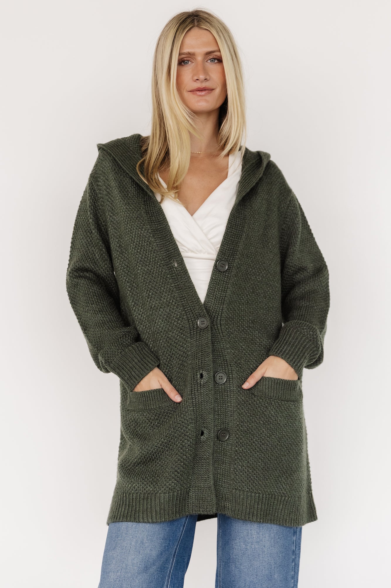 Three-quarter side view of Katrine cardigan in deep green highlighting oversized fit, ribbed cuffs, and textured chunky knit fabric on the sleeve.