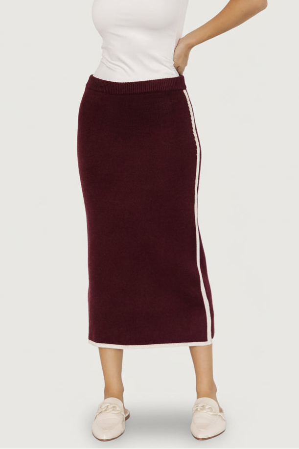 Front view of the Ava Knit Midi Skirt in wine on model, showing mid-rise elastic waistband and cream piping details across the hip.