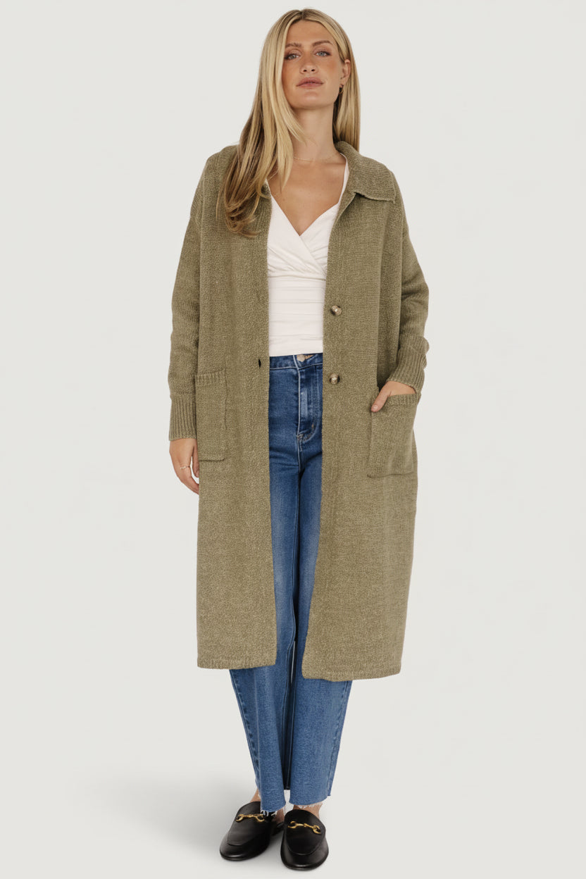 Model wearing heathered olive longline button cardigan, front view showing wide ribbed collar, patch pockets, and two-button waist.
