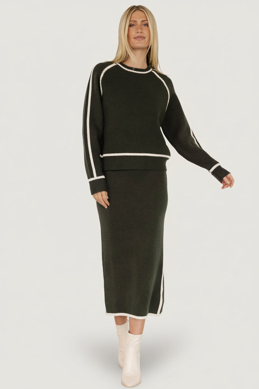 Model styling the dark green sweater paired with the matching Ava Knit Midi Skirt, illustrating a coordinated outfit option.