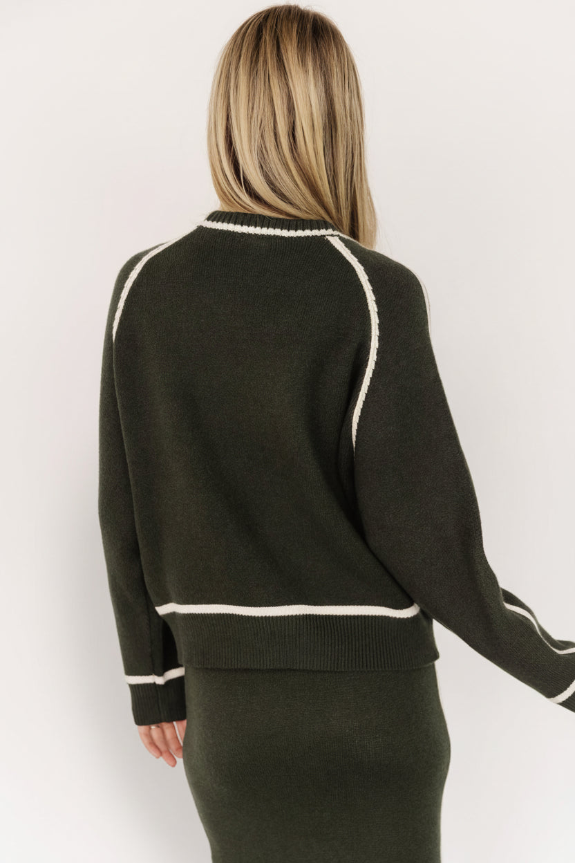 Side profile of the dark green knit sweater showing loose-fit sleeve, wide-ribbed cuff, and the soft woven texture up close.