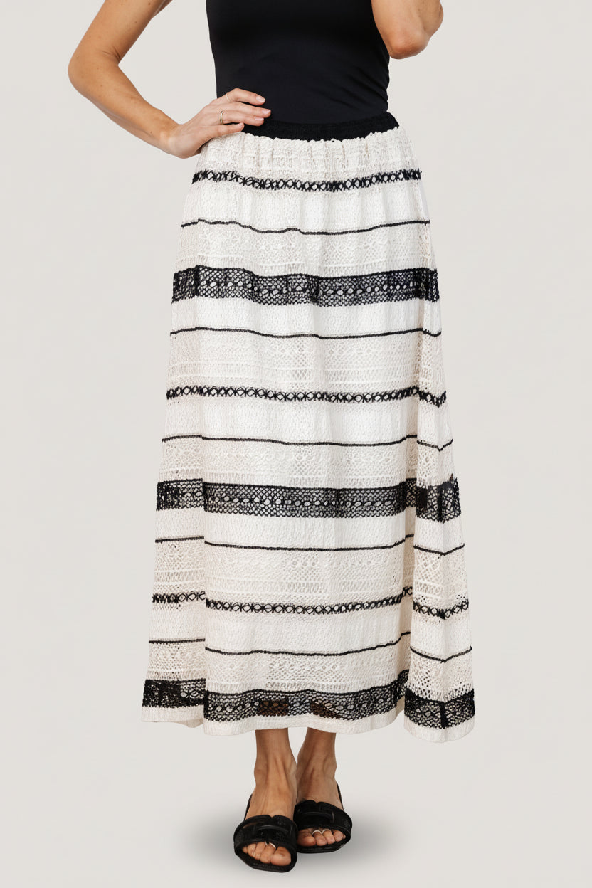 Front model view of Alondra woven A-line skirt in cream and black, showing textured weave, elastic waist, and lining.