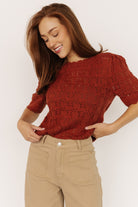 Close-up of Serenity Knit Sweater Top in rust showing open-knit holes, scalloped trim, and soft 50/50 cotton-acrylic yarn texture.
