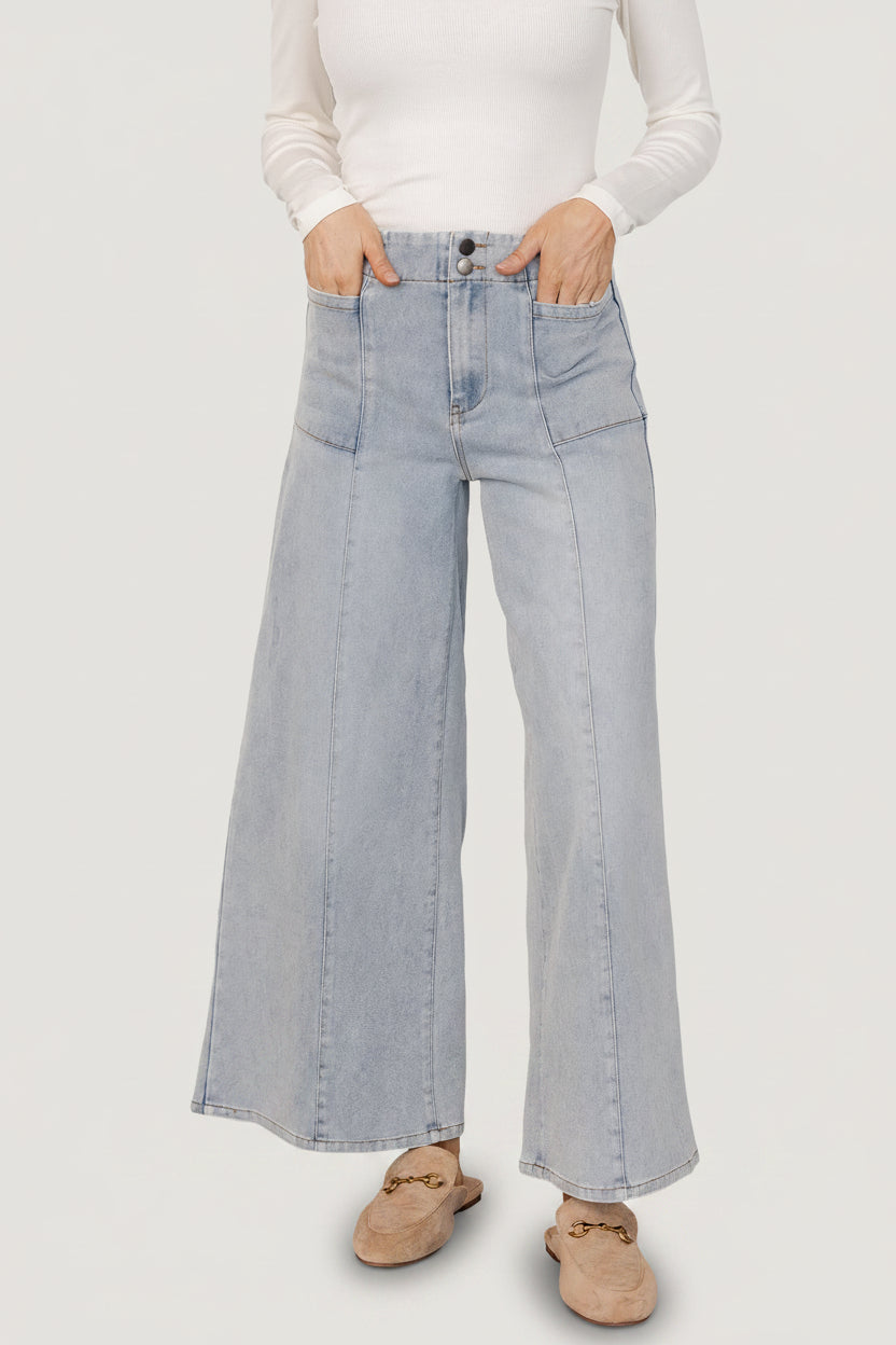 Front view of Emmi mid-rise wide-leg jeans in light wash worn by model, showing full-length flare and visible front pockets for styling.
