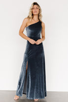 Back and drape detail of the Tatiana velvet one-shoulder maxi dress in slate blue, showing the skirt's subtle movement and lining.