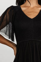 Close-up of Swiss dotted tulle overlay and fine dotted texture with lined interior visible through the sheer short sleeves of the dress.
