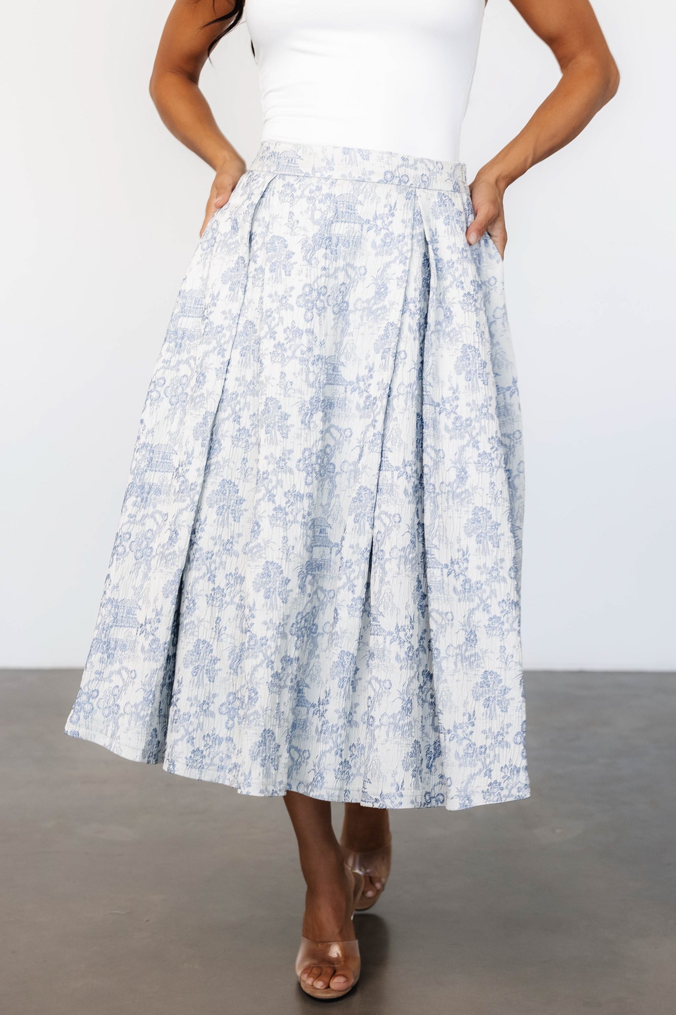 Studio front view of Jeanne pleated midi skirt in pearl with light blue toile, showing box pleats and banded waist.
