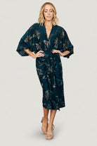 Front view of the Shaneen ruched midi dress in jade floral shimmer on model, showing deep V-neck, ruched waist and center slit.