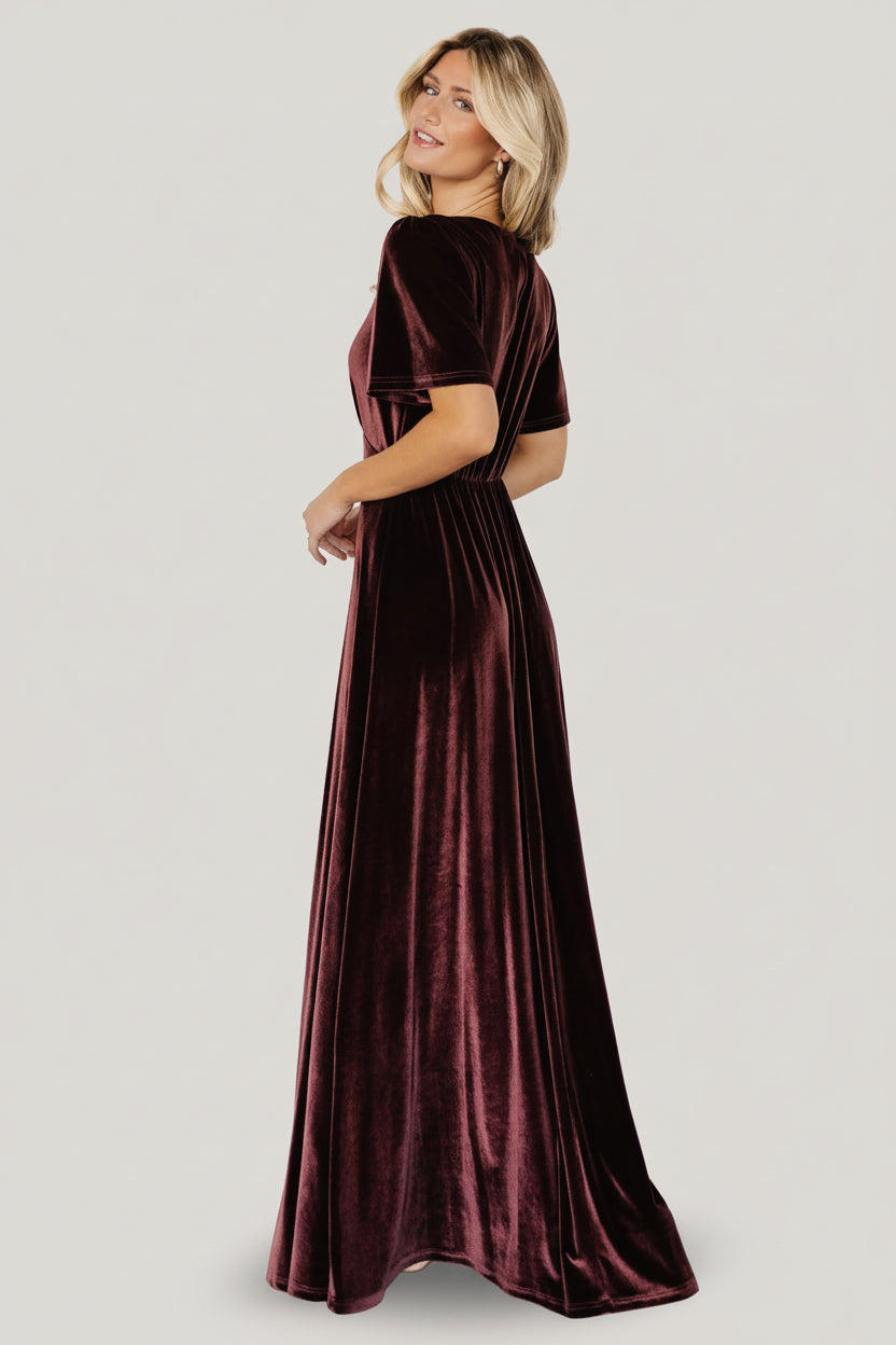 Editorial image of the Clove velvet gown in motion, emphasizing the flowing skirt, flattering empire silhouette, and the soft drape of the stretch velvet fabric.