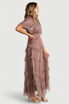 Styled flat-lay of Magdalena Tulle Maxi Dress in dusty mink showing the tiered ruffle construction, square neckline, and fabric texture.