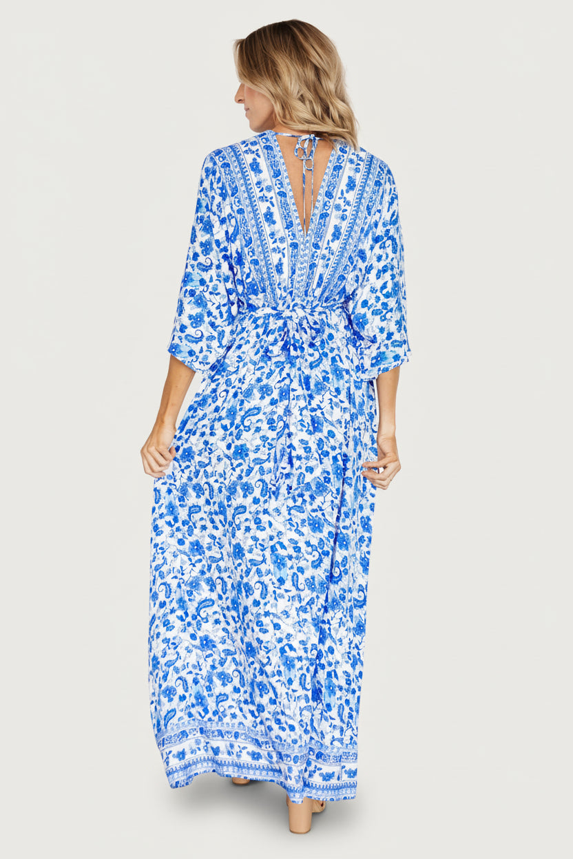 Model walking to show movement of unlined maxi skirt and left leg slit in blue and white Watson kimono dress.