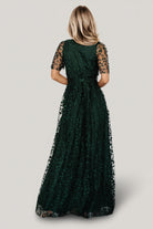 Three-quarter model shot showing short unlined sleeves and textured vine embossing on dark green organza fabric, highlighting sleeve detail.