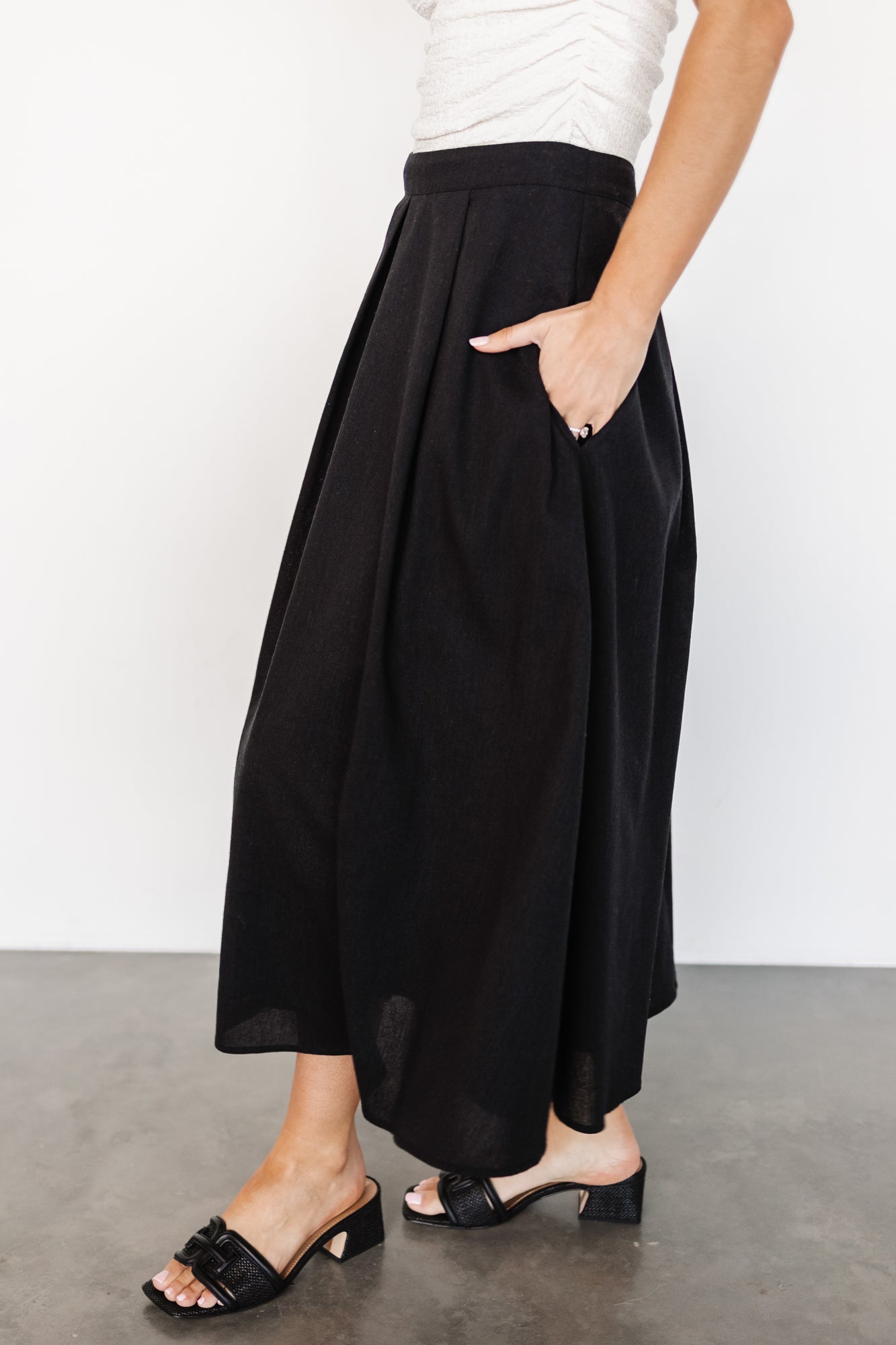 Detail image of the Katie pleated midi skirt in black focusing on fabric texture, stitch lines and the smooth, fully lined interior for coverage.