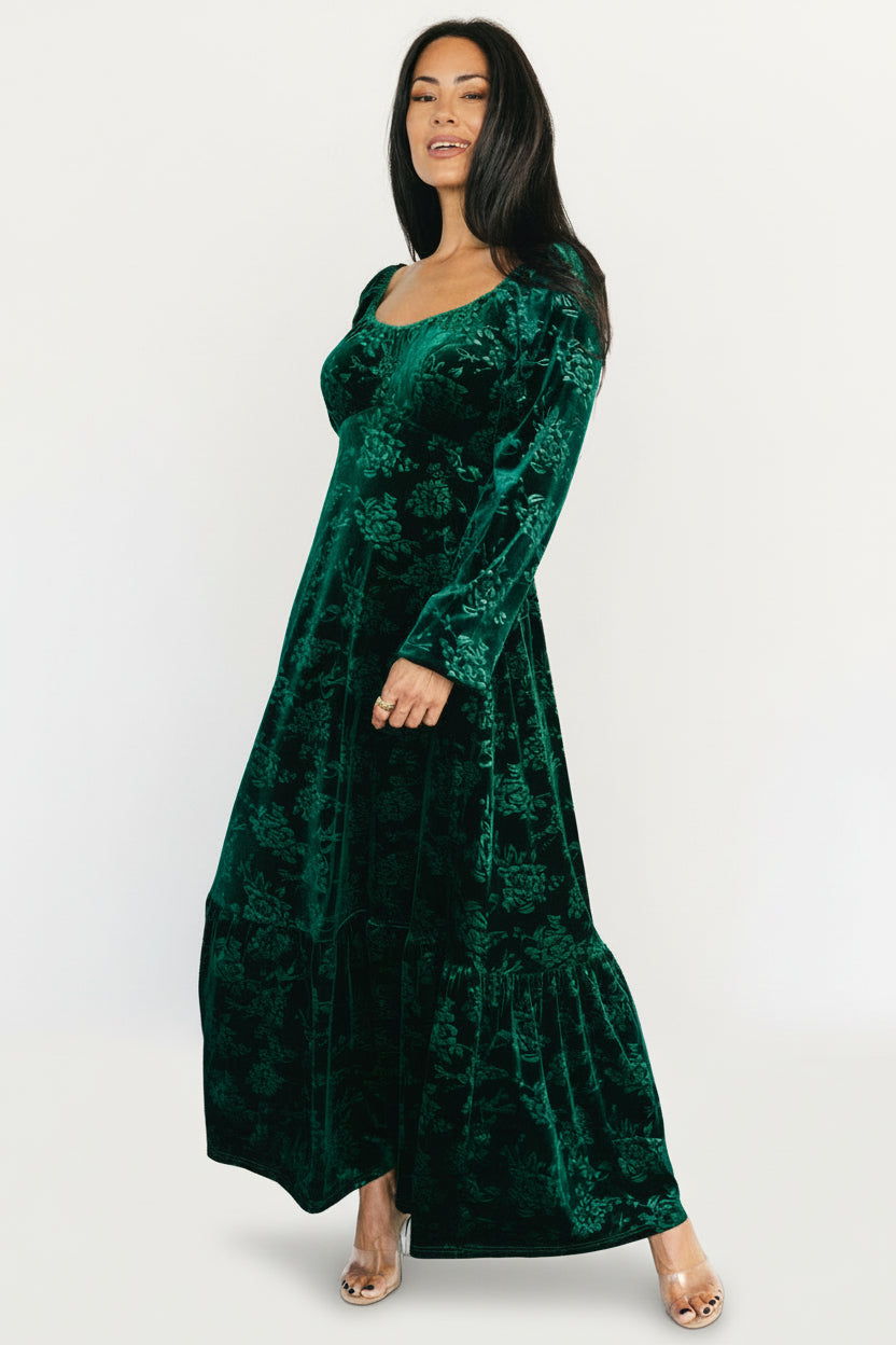Styled look of the Audra emerald velvet dress in a holiday setting, showing overall fit, movement and embossed floral detail.