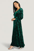 Side view showing the right-side zipper detail and smooth silhouette of the emerald Audra embossed velvet maxi dress.