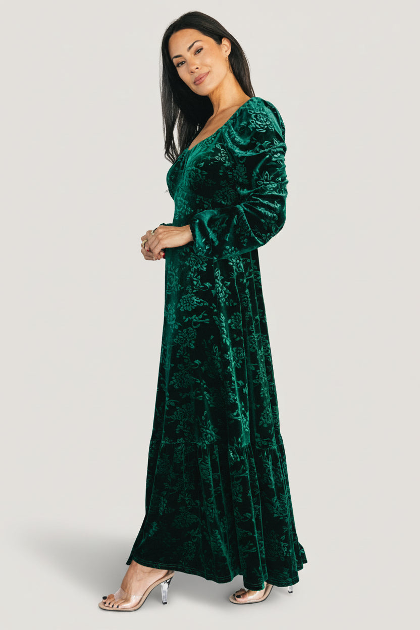 Side view showing the right-side zipper detail and smooth silhouette of the emerald Audra embossed velvet maxi dress.