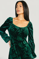 Close-up of embossed velvet floral pattern on the Audra dress showing dimensional burnt-out texture and rich emerald color.