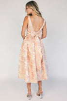 Model wearing a peach floral jacquard midi dress with a square neckline, wide tank straps, and a fitted bodice.