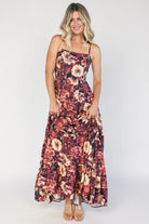 Model wearing a deep berry floral maxi dress with a square neckline, adjustable spaghetti straps, and a smocked back bodice.