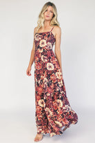 Model wearing a deep berry floral maxi dress with a square neckline, adjustable spaghetti straps, and a smocked back bodice.