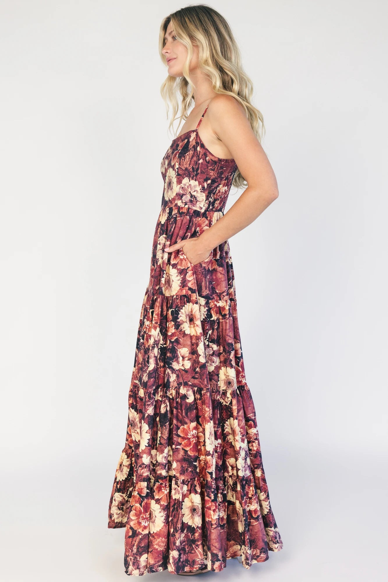 Model wearing a deep berry floral maxi dress with a square neckline, adjustable spaghetti straps, and a smocked back bodice.