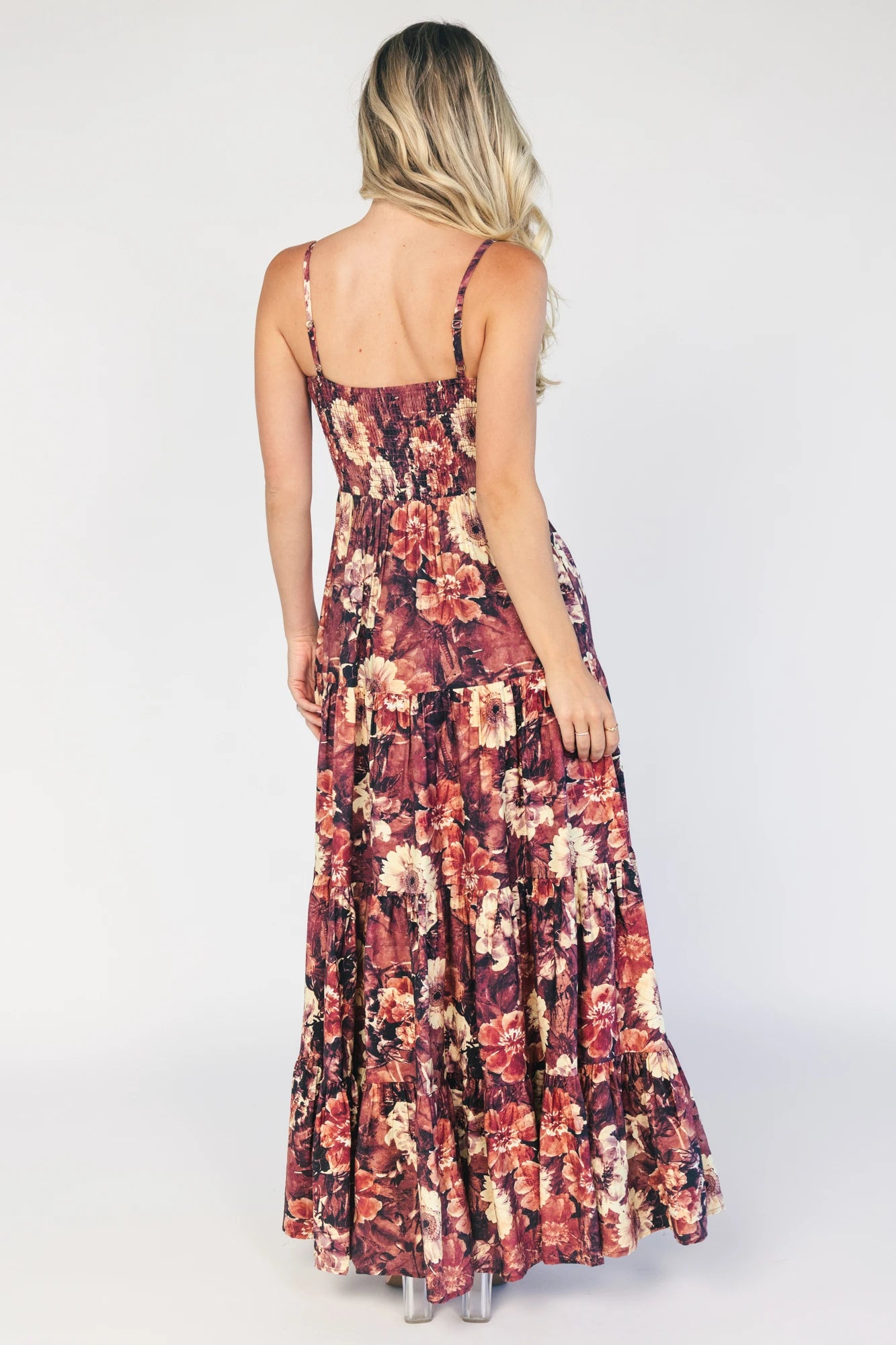 Model wearing a deep berry floral maxi dress with a square neckline, adjustable spaghetti straps, and a smocked back bodice.