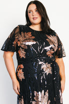 Model wearing dress in motion to showcase the full maxi skirt, sequin sparkle, and elegant drape from waist to hem.