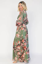 Model wearing a green floral maxi dress with a V-neckline, long bishop sleeves, and a gathered waist with a smocked back.