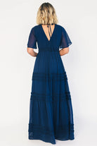 Model wearing a navy chiffon maxi dress with a surplice V-neckline, short ruffled sleeves, and an elastic empire waist.