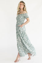 Close-up of the ivory floral print on dusty sage fabric with visible smocking and button-front texture.
