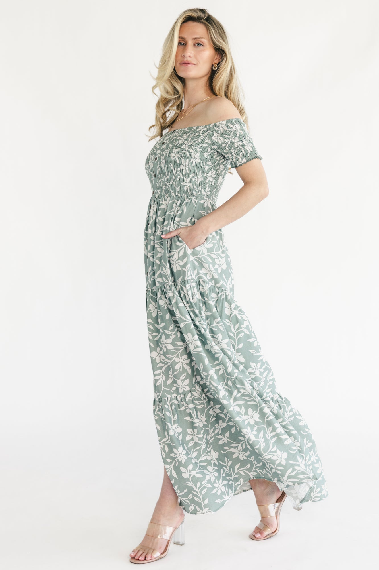 Close-up of the ivory floral print on dusty sage fabric with visible smocking and button-front texture.