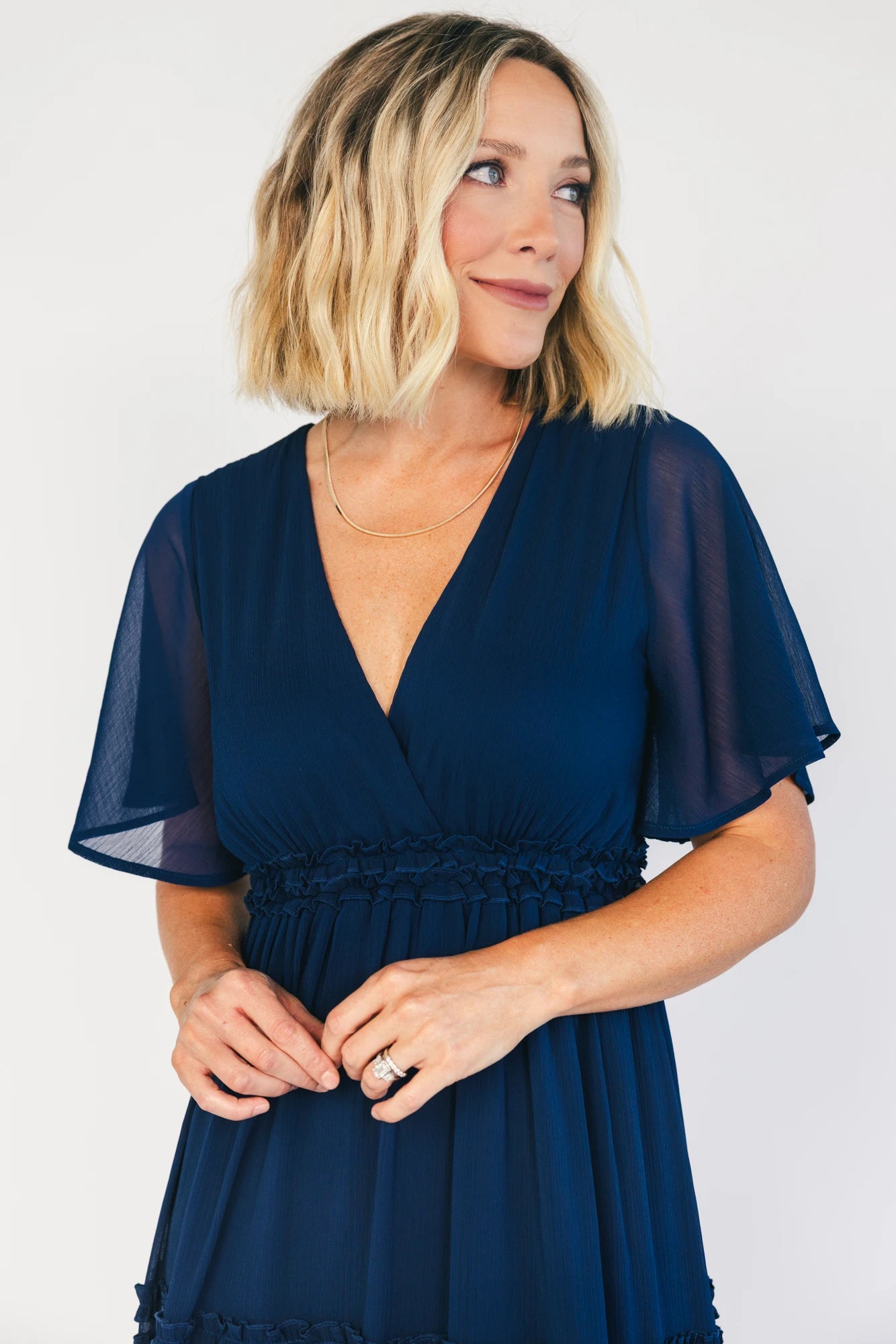 Model wearing a navy chiffon maxi dress with a surplice V-neckline, short ruffled sleeves, and an elastic empire waist.