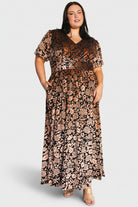 Model wearing the Leslie velvet maxi dress in Black + Bronze, angled three-quarter view showing short puff sleeves and fabric texture.
