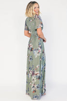 Model wearing a sage floral maxi dress with a deep V-neckline, short flutter sleeves, and an empire waist.