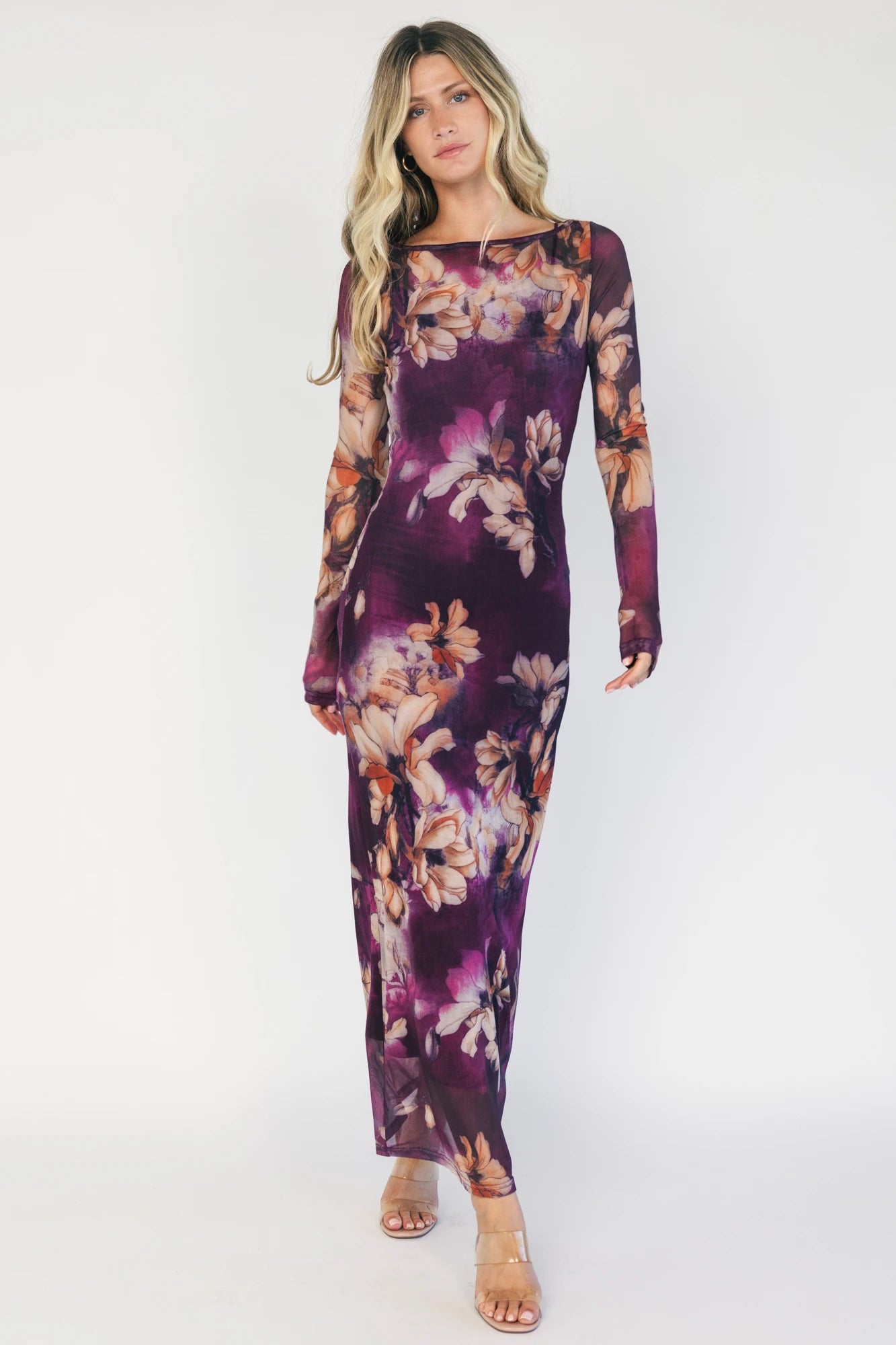 Model wearing a purple floral mesh midi dress with a round neckline, long sheer sleeves, and a fitted bodycon silhouette.