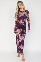 Model wearing a purple floral mesh midi dress with a round neckline, long sheer sleeves, and a fitted bodycon silhouette.