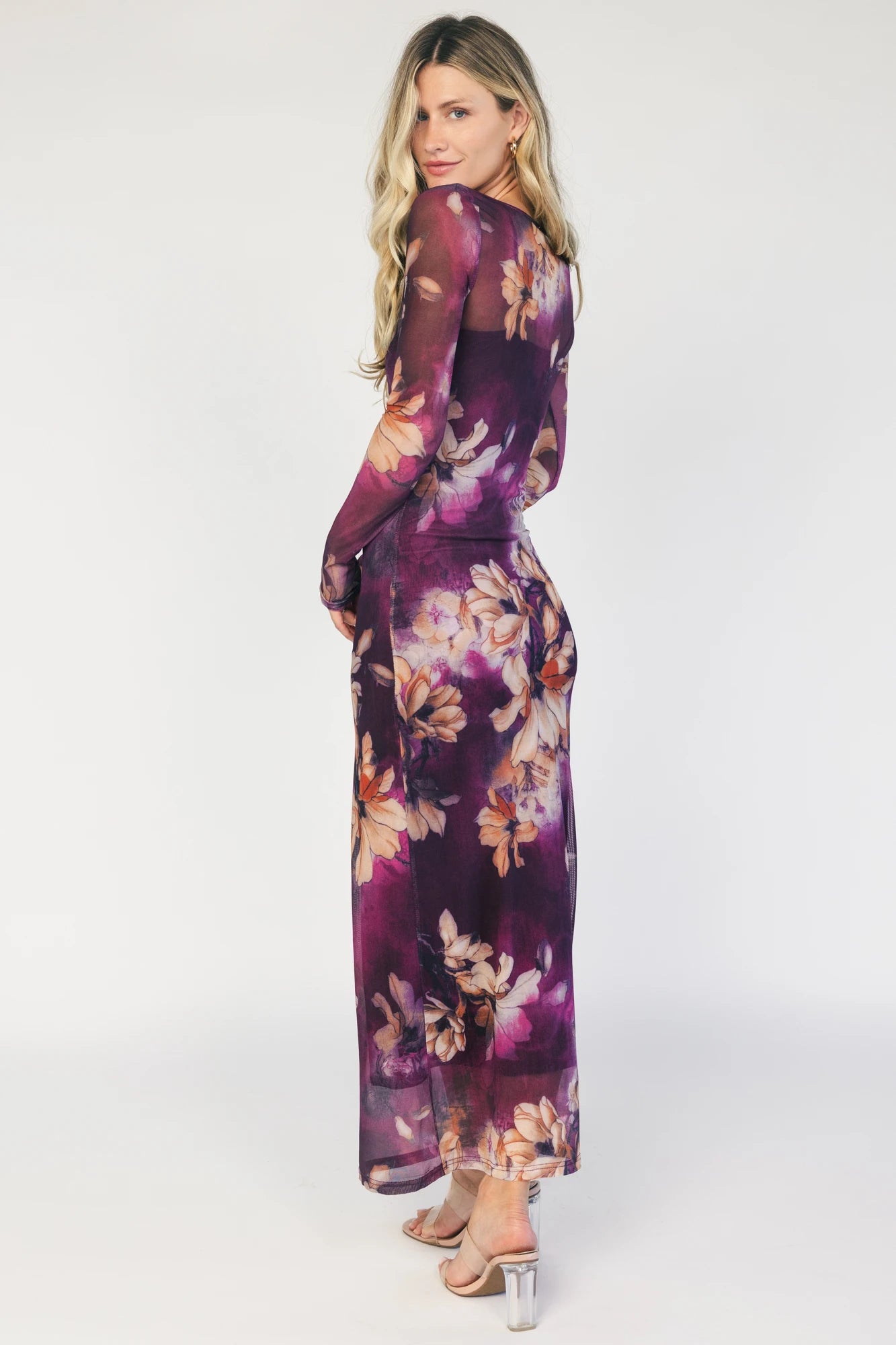 Model wearing a purple floral mesh midi dress with a round neckline, long sheer sleeves, and a fitted bodycon silhouette.