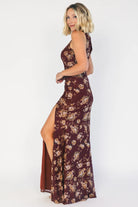 Model wearing a mahogany floral maxi dress with a high neckline, sleeveless fitted bodice, and ruched side detailing.