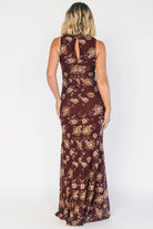 Model wearing a mahogany floral maxi dress with a high neckline, sleeveless fitted bodice, and ruched side detailing.