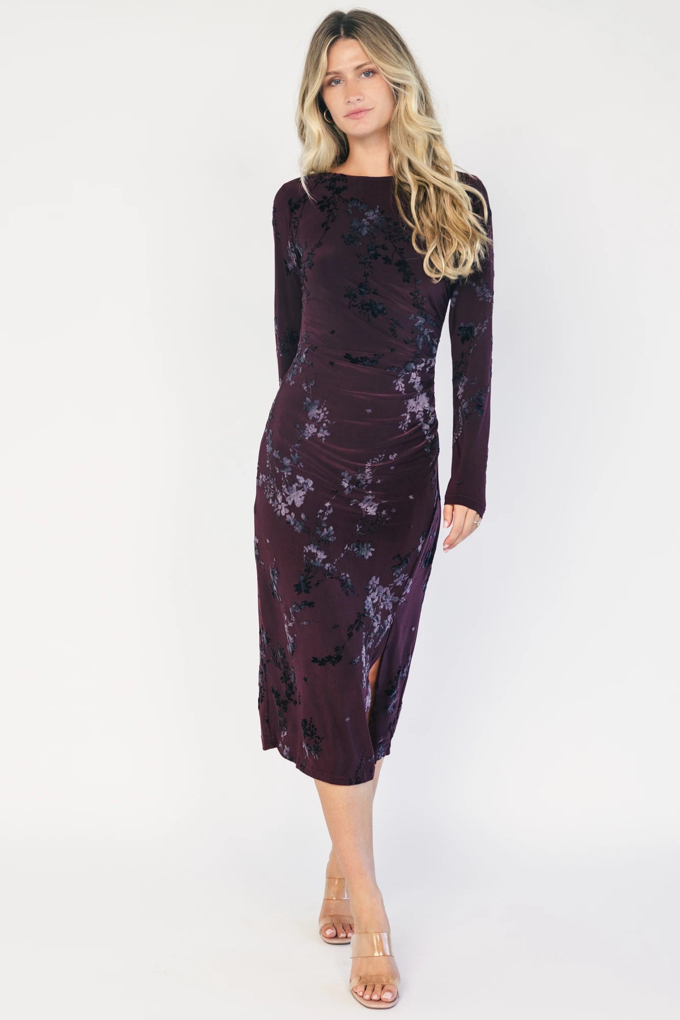 Model wearing a dark plum velvet floral midi dress with a boat neckline, long sleeves, and a fitted silhouette.